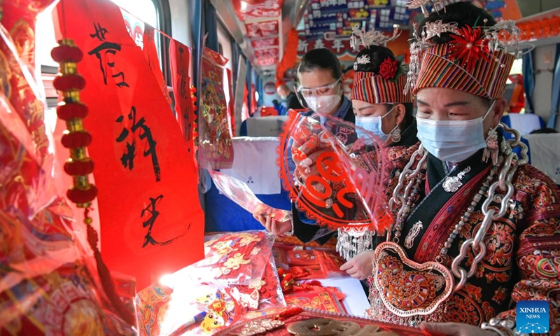 Passengers select new year decorations on train No. 5640 in southwest China's Guizhou Province, Jan. 10, 2023. The pair of slow trains No. 5640 and No. 5639 run in Guizhou Province between Yuping Dong Autonomous County of Tongren City and Guizhou's capital Guiyang City. The trains pass through several townships in Qiandongnan Miao and Dong Autonomous Prefecture, connecting more than 100 ethnic minority villages along the 337-km route.(Photo: Xinhua)
