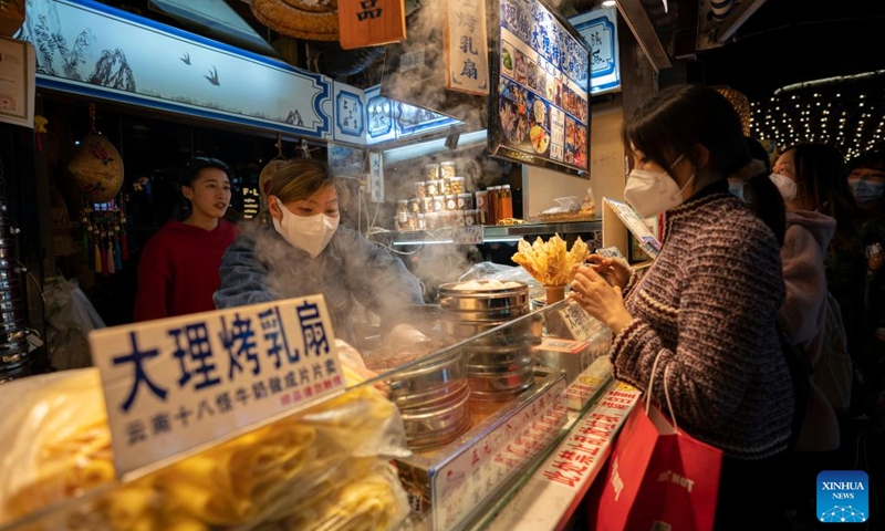 Residents buy snacks in the Nanqiang Street of Kunming, southwest China's Yunnan Province, Jan. 11,2023. The street, located in downtown Kunming, has seen a robust recovery of the nighttime economy. Tourists here can experience local food culture and nightlife of Kunming.(Photo: Xinhua)