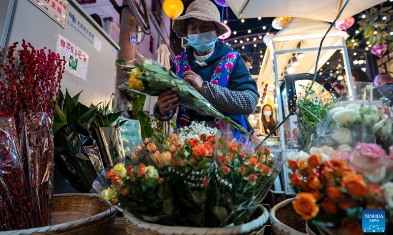 A vendor arranges flowers for sale in the Nanqiang Street of Kunming, southwest China's Yunnan Province, Jan. 11, 2023. The street, located in downtown Kunming, has seen a robust recovery of the nighttime economy. Tourists here can experience local food culture and nightlife of Kunming.(Photo: Xinhua)