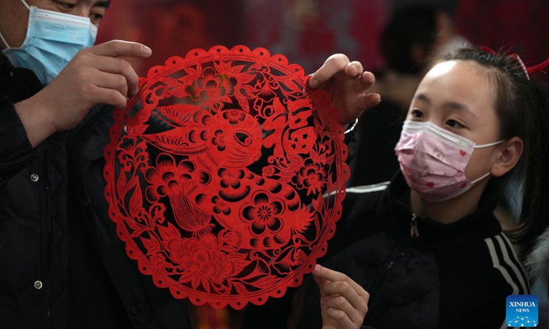 An artist shows a rabbit-themed paper-cutting work to a child at a cultural studio in Xinhua District of Shijiazhuang, north China's Hebei Province, Jan. 12, 2023. Cultural activities promoting intangible cultural heritages were held in Xinhua District to greet the upcoming Chinese Lunar New Year.(Photo: Xinhua)
