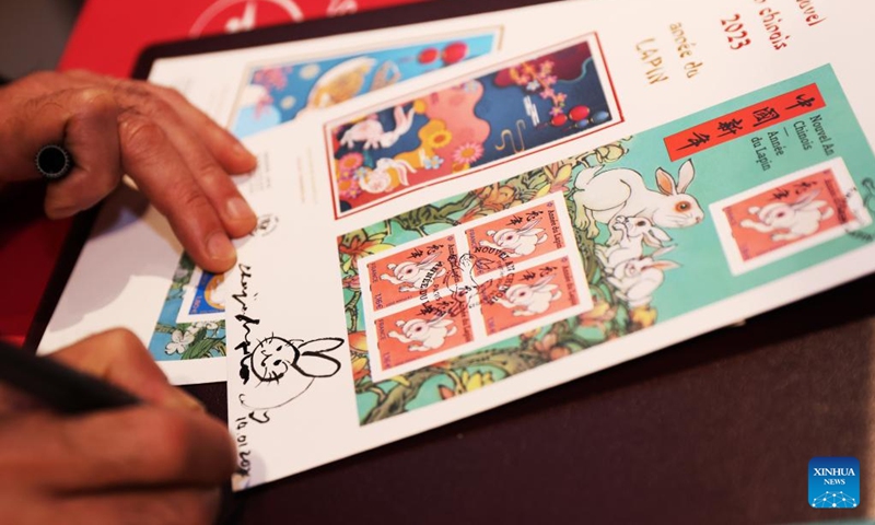 Chinese artist Chen Jianghong signs on the Year of the Rabbit commemorative stamps designed by him during a launching ceremony in Paris, France, Jan. 14, 2023. (Xinhua/Gao Jing)