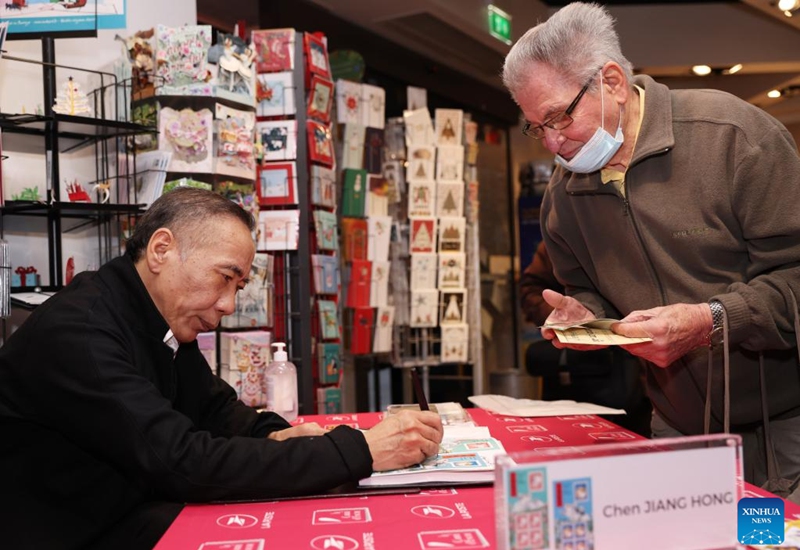 Chinese artist Chen Jianghong signs on the Year of the Rabbit commemorative stamps designed by him during a launching ceremony in Paris, France, Jan. 14, 2023. (Xinhua/Gao Jing)