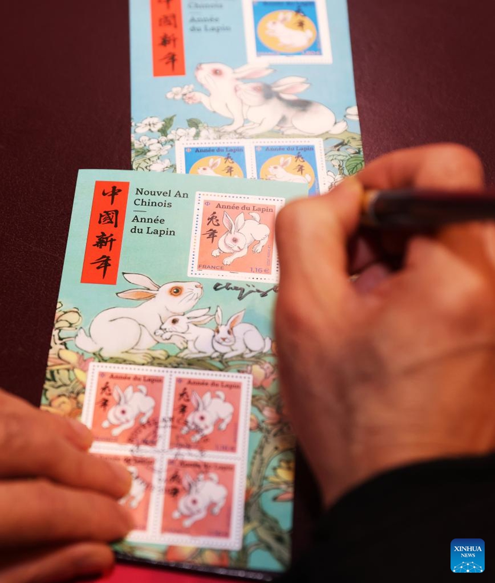 Chinese artist Chen Jianghong signs on the Year of the Rabbit commemorative stamps designed by him during a launching ceremony in Paris, France, Jan. 14, 2023. (Xinhua/Gao Jing)