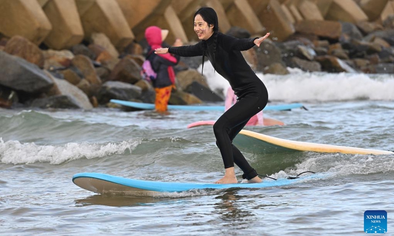 A tourist goes surfing at Riyue Bay in Wanning, south China's Hainan Province, Jan. 13, 2023. Surfing has become a symbol of Wanning thanks to its unique geographical and climatic advantages. (Xinhua/Guo Cheng)