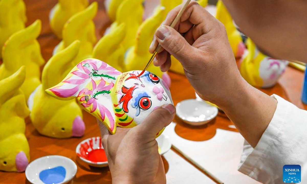 A folk artist colours a piece of work at a clay figurine workshop in Yutian County, north China's Hebei Province, Jan. 16, 2023. As the Chinese Lunar New Year of the Rabbit approaches, decorative items and handicraft works featuring the image of the rabbit, one of the 12 Chinese Zodiac animals, are sweeping the streets, adding festive atmosphere to the event. (Photo by Liu Mancang/Xinhua)
