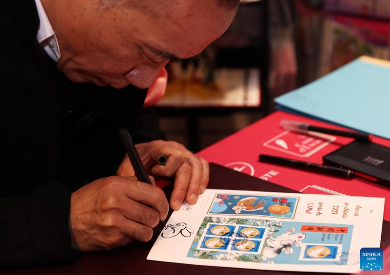 Chinese artist Chen Jianghong signs on the Year of the Rabbit commemorative stamps designed by him during a launching ceremony in Paris, France, Jan. 14, 2023. (Xinhua/Gao Jing)