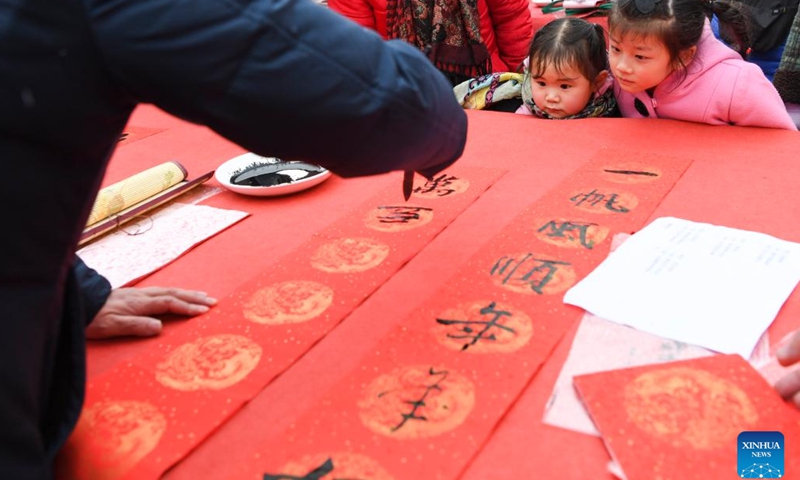Kids look on as a calligrapher writes Spring Festival couplets for residents during a couplets writing activity in Yongchuan District, southwest China's Chongqing, Jan. 16, 2023.(Photo: Xinhua)