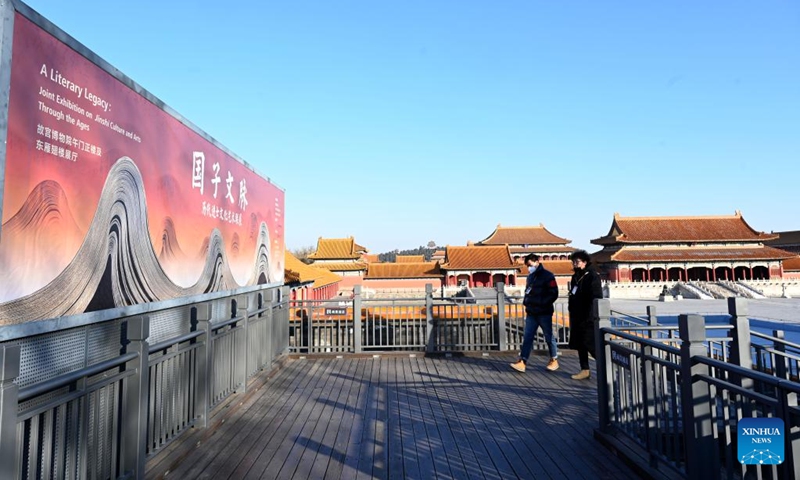 Two citizens walk past a poster of the Joint Exhibition on Jinshi Culture and Arts Through the Ages at the Palace Museum in Beijing, capital of China, Jan. 16, 2023. A Joint Exhibition on Jinshi Culture and Arts Through the Ages, featuring Chinese ancient imperial scholars, kicked off at the Wumen Exhibition Hall of the Palace Museum. Some 179 selected artworks since the Tang Dynasty (618-907) were on display.(Photo: Xinhua)