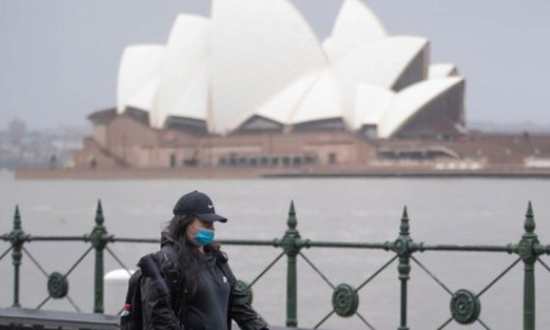A woman walks past Sydney Opera House in Sydney, Australia, on July, 6, 2022. Photo: Xinhua