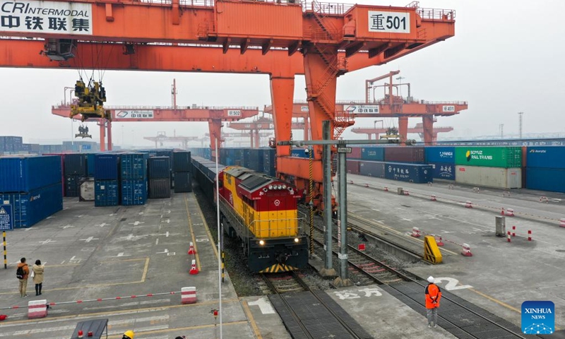This aerial photo shows a rail-sea intermodal freight train carrying containers of goods, including cars, motorcycles, engines, and sodium carbonate, at Tuanjie Village Central Station in southwest China's Chongqing, Jan. 22, 2023. It was the city's first outbound cargo train of the New International Land-Sea Trade Corridor in the Year of the Rabbit. Goods on the train will be transported to Qinzhou port on the country's southern coast, from where they will be shipped to Indonesia, the Philippines, Australia, and some other countries and regions. (Xinhua/Liu Chan)