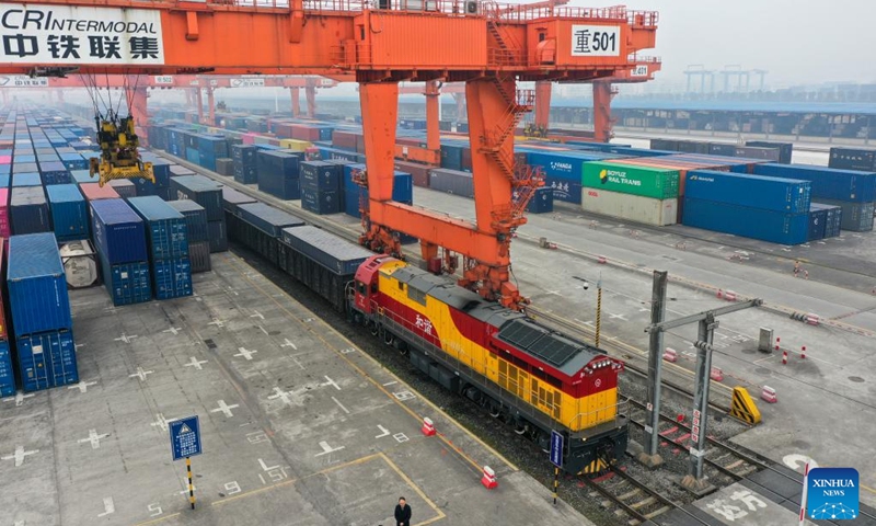 This aerial photo shows a rail-sea intermodal freight train carrying containers of goods, including cars, motorcycles, engines, and sodium carbonate, at Tuanjie Village Central Station in southwest China's Chongqing, Jan. 22, 2023. It was the city's first outbound cargo train of the New International Land-Sea Trade Corridor in the Year of the Rabbit. Goods on the train will be transported to Qinzhou port on the country's southern coast, from where they will be shipped to Indonesia, the Philippines, Australia, and some other countries and regions. (Xinhua/Liu Chan)