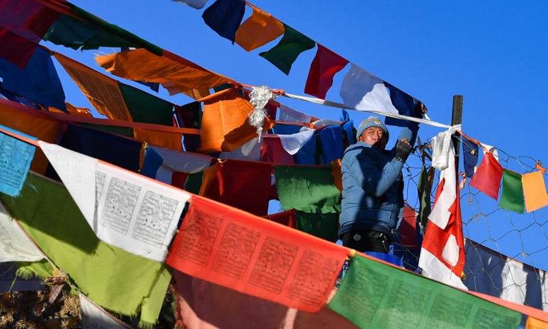 A man hangs prayer flags on a mountain in Xigaze, southwest China's Tibet Autonomous Region, Jan. 24, 2023. Following the tradition, people here went early in the morning to hang new prayer flags on top of mountains and their house roofs to celebrate New Year under the Tibetan calendar. (Xinhua/Jigme Dorje)