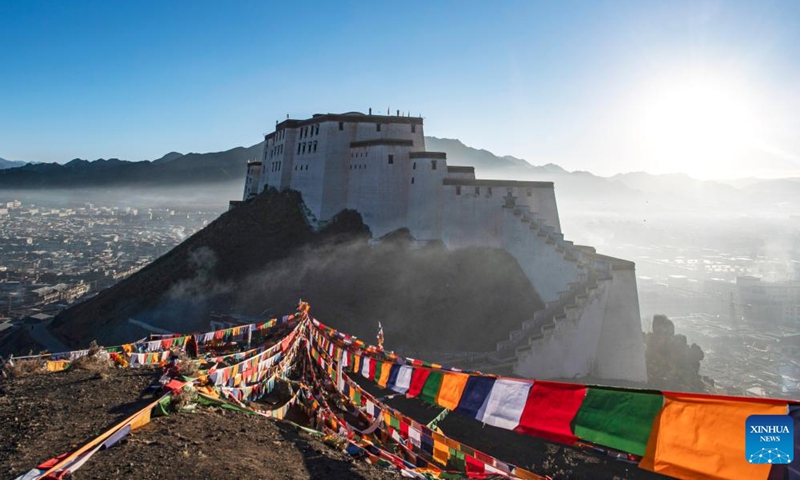 A man hangs prayer flags on a mountain in Xigaze, southwest China's Tibet Autonomous Region, Jan. 24, 2023. Following the tradition, people here went early in the morning to hang new prayer flags on top of mountains and their house roofs to celebrate New Year under the Tibetan calendar. (Xinhua/Sun Fei)