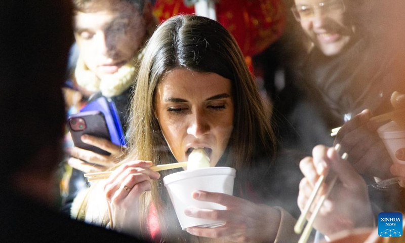 A woman tastes dumplings during an event celebrating the Chinese Lunar New Year in Belgrade, Serbia, Jan. 21, 2023. (Photo by Wang Wei/Xinhua)