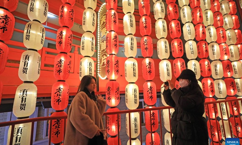 A woman poses for pictures with lanterns at Huangsi Temple Fair during the Spring Festival holiday in Shenyang, capital of northeast China's Liaoning Province, Jan. 23, 2023. Various activities were held here at the 6-day fair, starting from Jan. 22, to celebrate the Spring Festival. (Xinhua/Yang Qing)