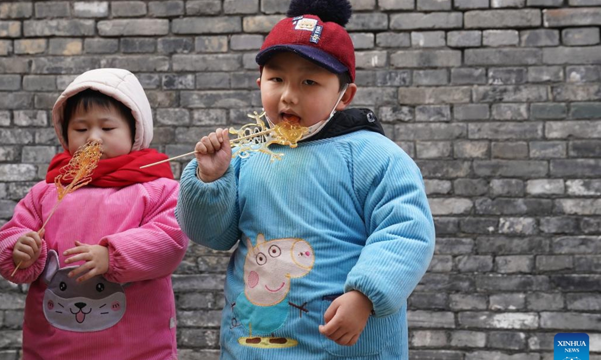Kids eat candy at a historical street area in Xuyi, east China's Jiangsu Province, Jan. 23, 2023. People enjoy various kinds of cuisine in China during the Spring Festival holiday. (Xinhua/Ji Chunpeng)


