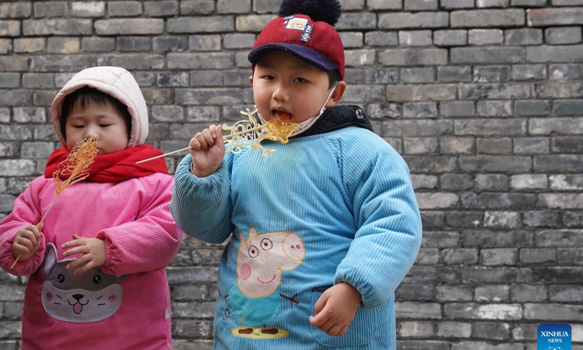 Kids eat candy at a historical street area in Xuyi, east China's Jiangsu Province, Jan. 23, 2023. People enjoy various kinds of cuisine in China during the Spring Festival holiday. (Xinhua/Ji Chunpeng)


