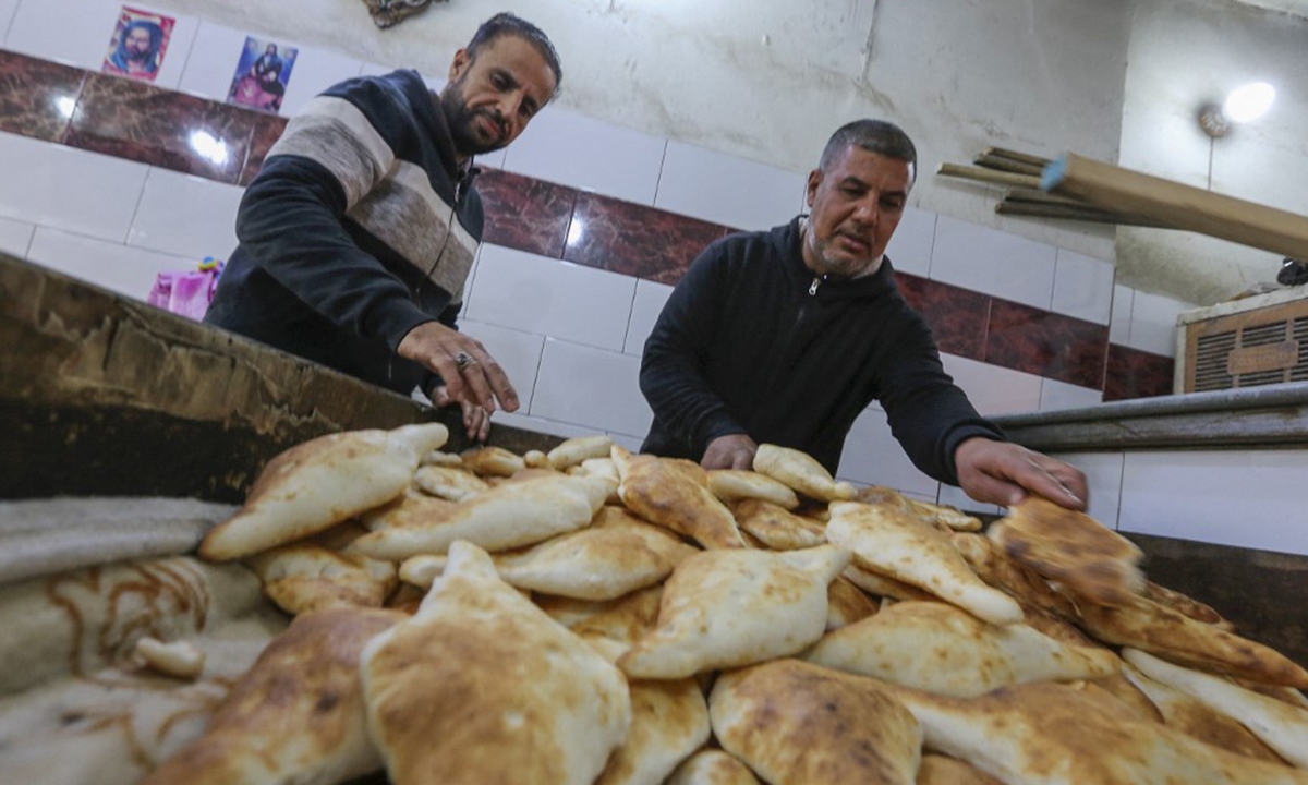 Bakery owner Abu Sajjad (right) checks freshly-baked loaves at his bakery for Samoon bread in al-Rashid street, in Iraq's capital Baghdad on January 14, 2023. Photo: AFP