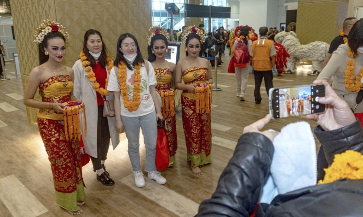 Two Chinese tourists and local dancers pose for photos at the Ngurah Rai International Airport in Bali, Indonesia, Jan 22, 2023. Photo:Xinhua