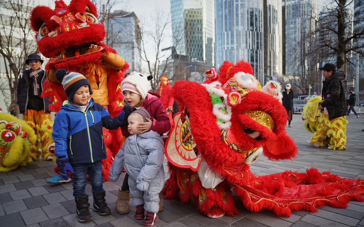 Foreign kids watch a lion dance performance during the Spring Festival in Beijing. Photo: IC 