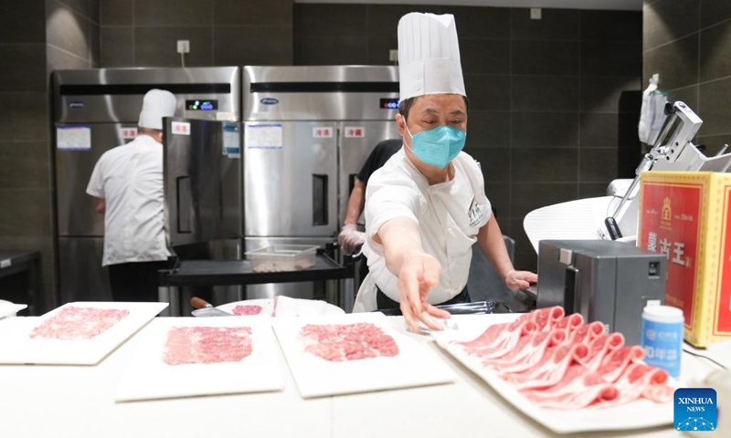 Chef Feng Bingshan (front) slices meat for the first customers at a restaurant on the first working day after the Spring Festival holiday in Beijing, capital of China, Jan. 28, 2023. Saturday marked the first day of work after the Spring Festival holiday in China.(Photo: Xinhua)