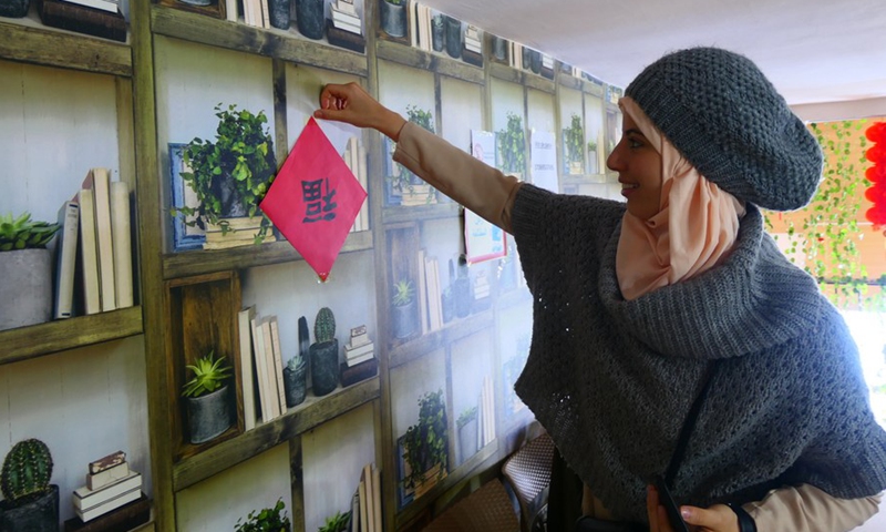 A Tunisian student pastes the Chinese character Fu in the Oriental Knowledge Bookstore in Tunis, Tunisia on Jan. 27, 2023.(Photo: Xinhua)