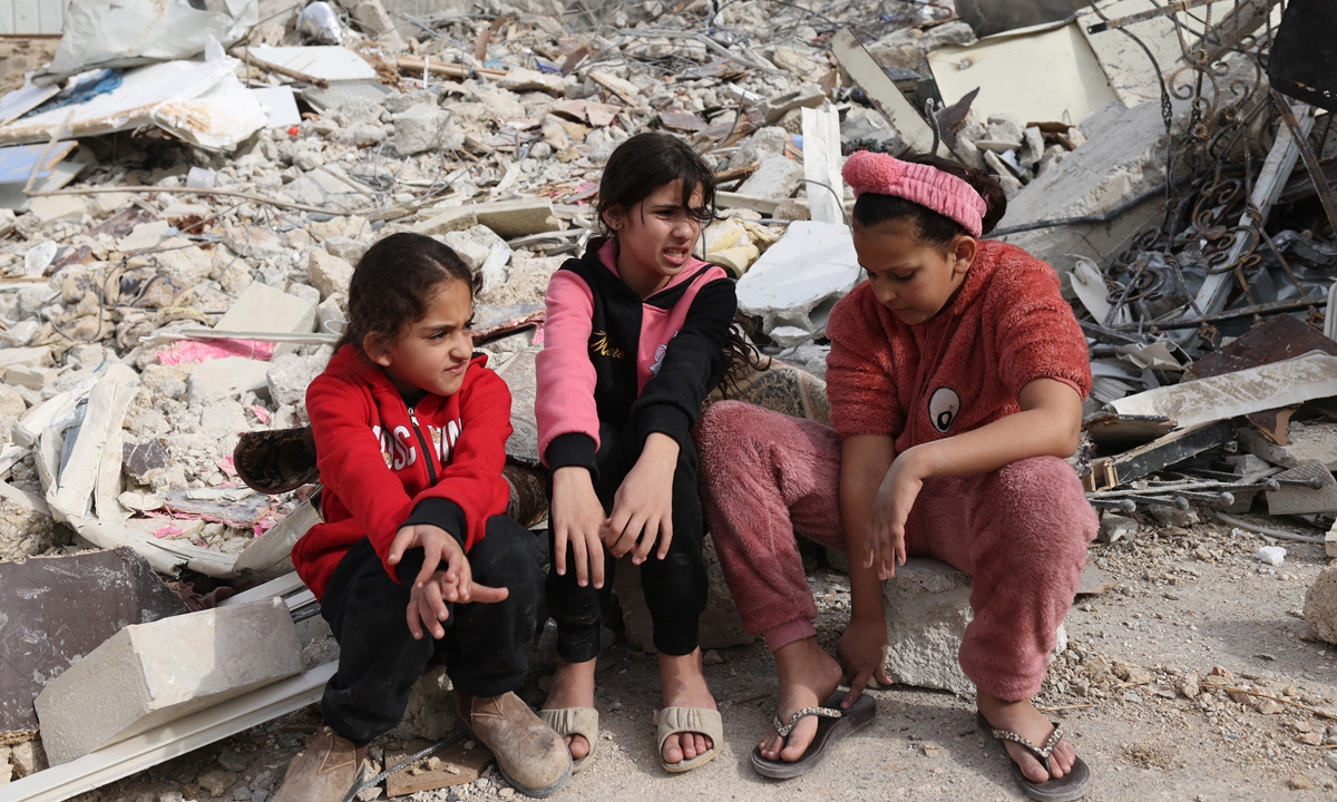 Palestinian girls sit in the debris of the house of Rateb Hatab Shukairat, after it was demolished by Israeli bulldozers, in the East Jerusalem neighbourhood of Jabal Mukaber on January 29, 2023. Photo: AFP