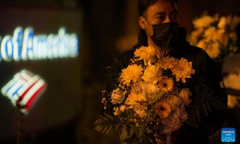 A man holds a bunch of flowers to mourn the victims of the shootings in Half Moon Bay in California, the United States, Jan. 31, 2023. People here on Tuesday evening attended the memorial service and candlelight procession held in Half Moon Bay to mourn the victims of the mass shootings in the city.(Photo: Xinhua)
