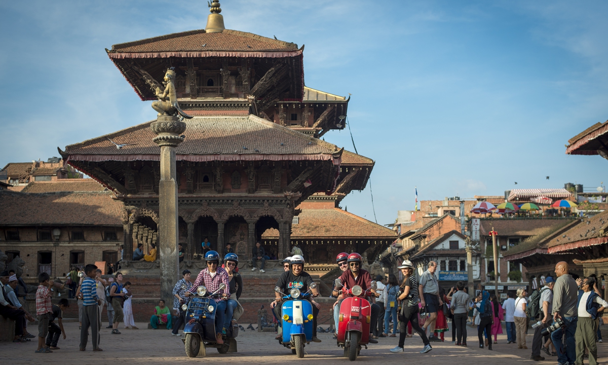 A group of people ride motorcycles through Patan Durbar Square, Kathmandu, Nepal. Photo: VCG