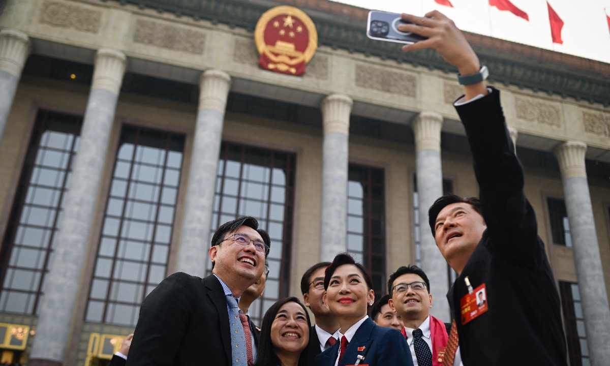 Deputies take a selfie in front of the Great Hall of the People after the second plenary session of the National People's Congress (NPC) in Beijing on March 7, 2023. Photo: AFP