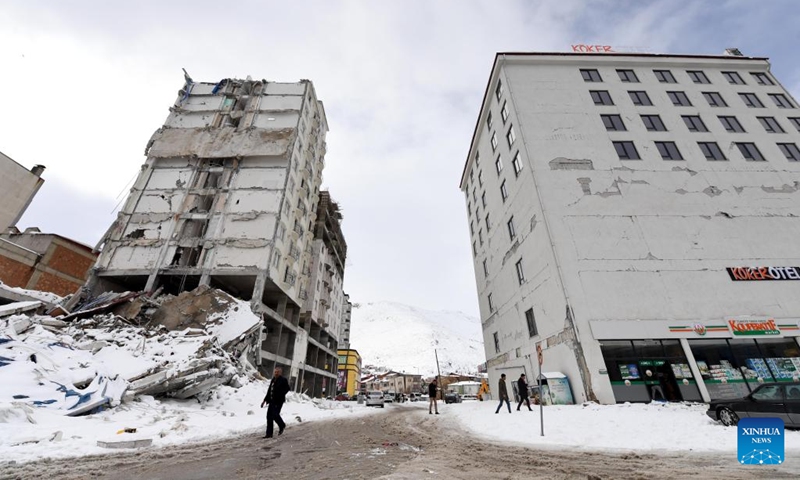 People walk past a damaged building in Elbistan district of Kahramanmaras Province, Türkiye, Feb. 7, 2023. The death toll from Monday's powerful earthquakes in southern Türkiye rose to 3,549, said Turkish President Recep Tayyip Erdogan upon declaring that a three-month state of emergency is enacted in 10 affected provinces.(Photo: Xinhua)