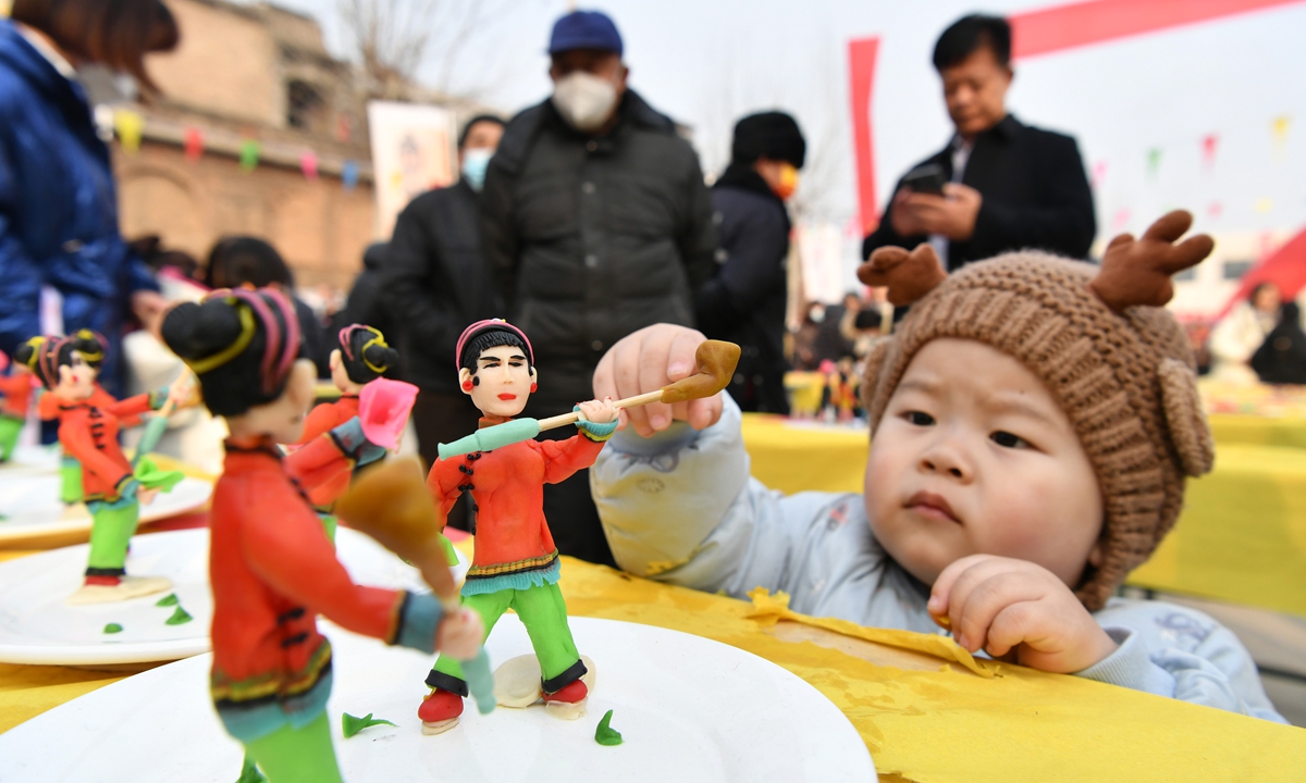 A kid is attracted by a group of dough figurines in Nanzhang village, Jingxing county, North China's Hebei Province, on February 8, 2023. Dough figurines in the village have a history of more than 200 years and have been selected into the provincial intangible cultural heritage list. Photo: VCG