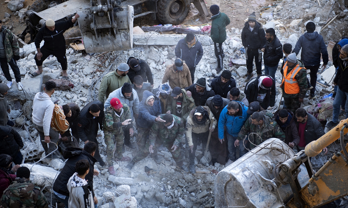 Residents search for victims and survivors amidst the rubble of a collapsed building in the town of Jableh, northwest of the Syrian capital Damascus, on February 8, 2023. Photo: AFP