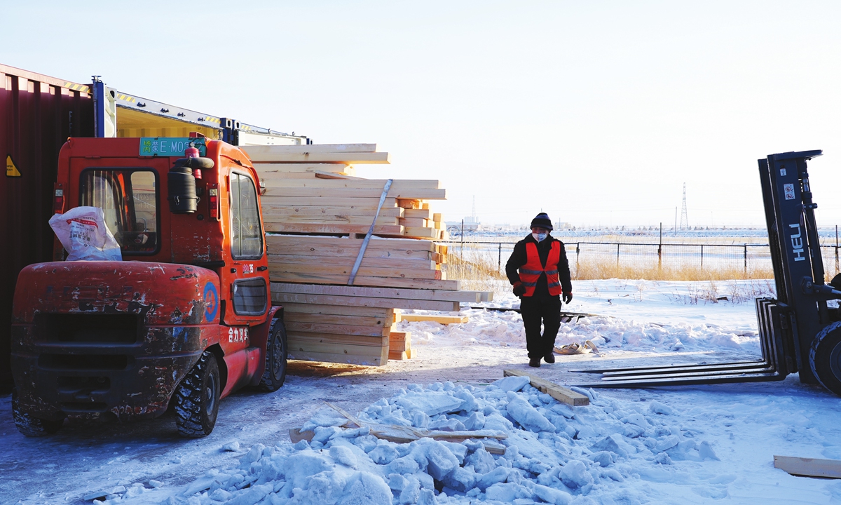 A worker offloads imported wood from a container and waits for customs officers to inspect the consignment at a container yard at the Manzhouli port on February 9, 2023. Photo: Pang Yue/GT