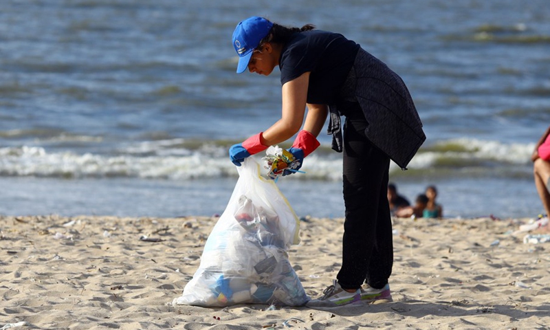 A woman collects waste from the beach in Alexandria, Egypt, Aug. 13, 2022.(Photo: Xinhua)