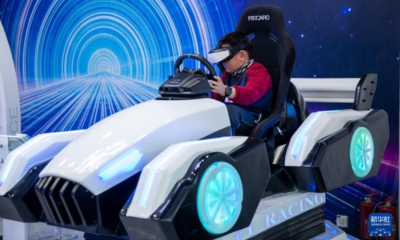 A visitor wearing a VR headset tries a driving simulator at an ice and snow metaverse experience center in Harbin, northeast China's Heilongjiang Province, Feb. 12, 2023. Recently, the ice and snow metaverse experience center at the Harbin Ice and Snow World in Harbin has drawn much attention. It enables visitors to enjoy the ice and snow scenery and activities regardless of the seasons.(Photo: Xinhua)