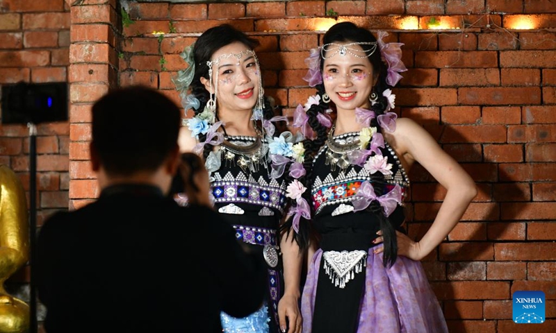 Tourists pose for photos at a night fair in Jinghong City of Xishuangbanna Dai Autonomous Prefecture, southwest China's Yunnan Province, Feb. 12, 2023. The night fair here has attracted a good many tourists, some of whom enjoyed a travel photo service in which photo studios provided traditional costumes and makeup to tourists.(Photo: Xinhua)