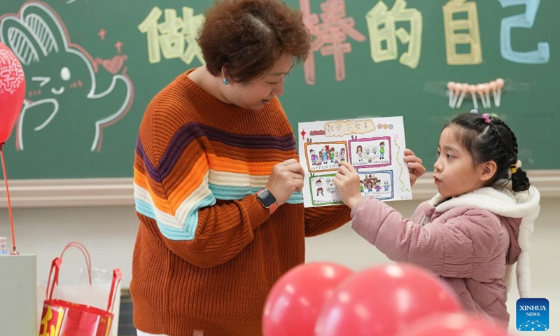 Pupil Guo Yizhi (R) displays her homework at a primary school in Chaoyang District in Beijing, capital of China, Feb. 13, 2023. Primary and middle school students in Beijing returned to school for the spring semester on Monday.(Photo: Xinhua)