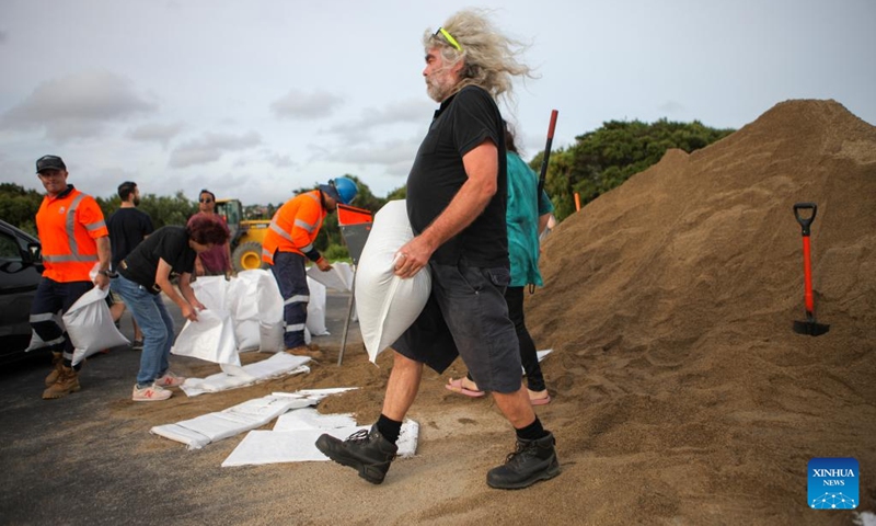 A resident carries a sandbag at a temporary storage site of sand in Auckland, New Zealand, Feb. 11, 2023. New Zealand's largest city Auckland set up temporary storage sites of sand and provided sandbags for residents to get prepared for new severe weather event. The last round of record rainfall has caused massive flooding to houses and properties since Jan. 27.(Photo: Xinhua)