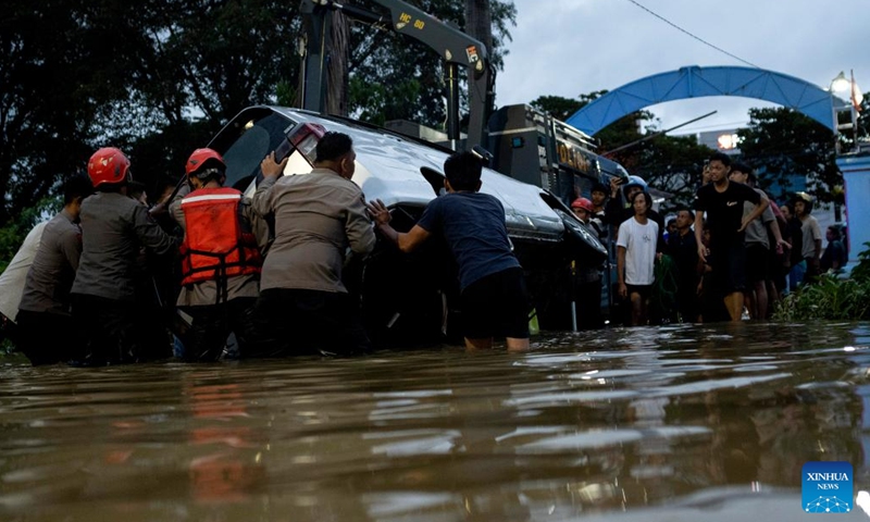People try to evacuate a car submerged by floodwater after heavy rain in Makassar, South Sulawesi, Indonesia, Feb. 13, 2023.(Photo: Xinhua)