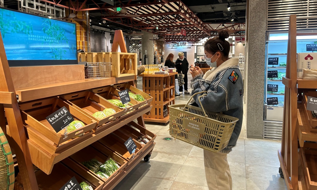 A customer takes a picture of organic vegetables on sale at a Muji store in Shanghai. photo: Qi Xijia/GT