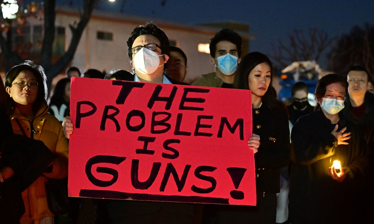 Local people hold a placard protesting gun violence at a memorial service held to pay respects to the victims of a local shooting in Monterey Park, California, on January 23, 2023. Photo: VCG