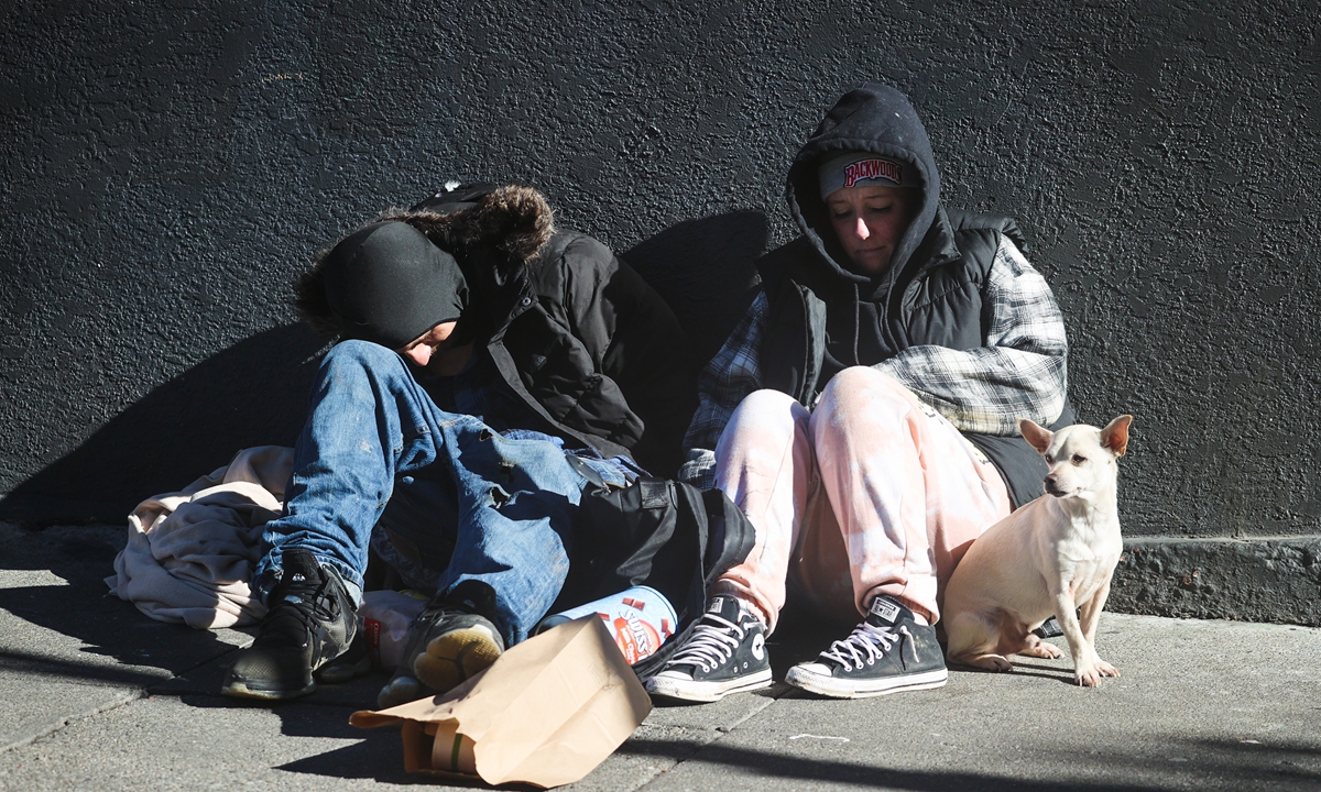 A homeless couple is seen on the sidewalk near City Hall in San Francisco, California on December 12, 2022. Photo: VCG