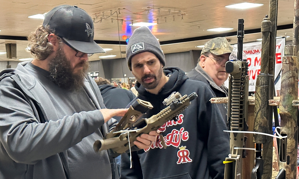 Two men inspect an AR-10 rifle at the Belle-Clair Fairgrounds & Expo Center Gun Show, in Belleville, US, on January 14, 2023, after the state of Illinois passed its 
