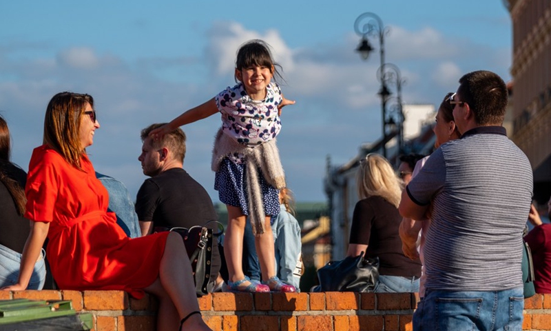 A girl enjoys herself on a brick wall in the Old Town of Warsaw, Poland, June 14, 2020. (Xinhua/Zhou Nan)