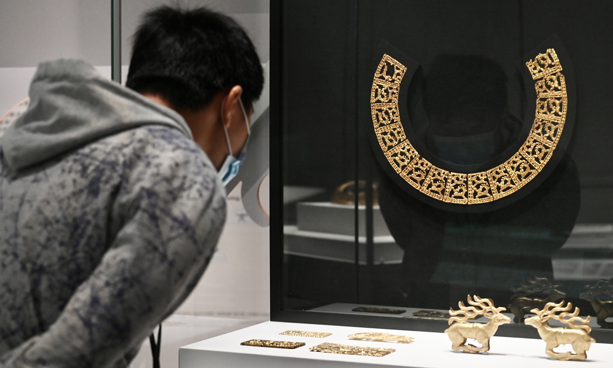 A visitor examines gold relics on display at the Hong Kong Palace Museum. Photo: VCG