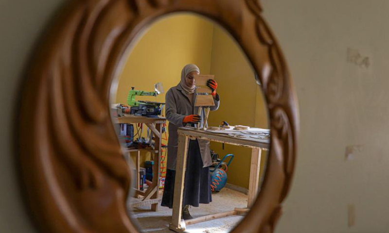 A woman makes wooden carvings at a workshop in Gaza City, Feb. 25, 2023. (Photo by Rizek Abdeljawad/Xinhua)