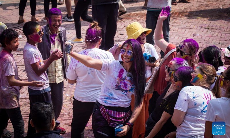 People smeared with colored powder take selfies during the celebration of Holi Festival at Patan Durbar Square in Lalitpur, Nepal, March 6, 2023.(Photo: Xinhua)