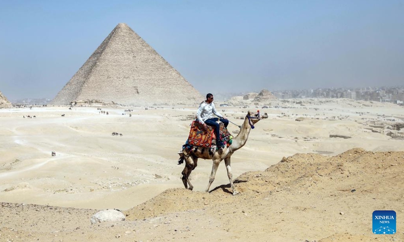 A man rides a camel near the Khufu Pyramid in Giza, Egypt, on March 2, 2023. A discovery of a nine-meter-long and 2.10-meter-wide corridor behind the Great Pyramid of Giza, known as Khufu Pyramid, was announced on Thursday.(Photo: Xinhua)
