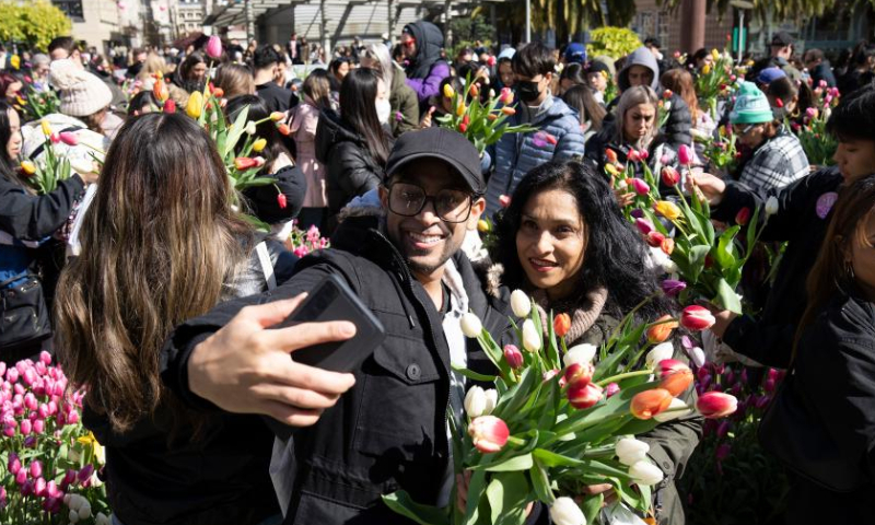People take selfies with tulip bouquets at a tulip show in celebration of the upcoming International Women's Day in Los Angeles, the United States, March 4, 2023. (Photo by Li Jianguo/Xinhua)